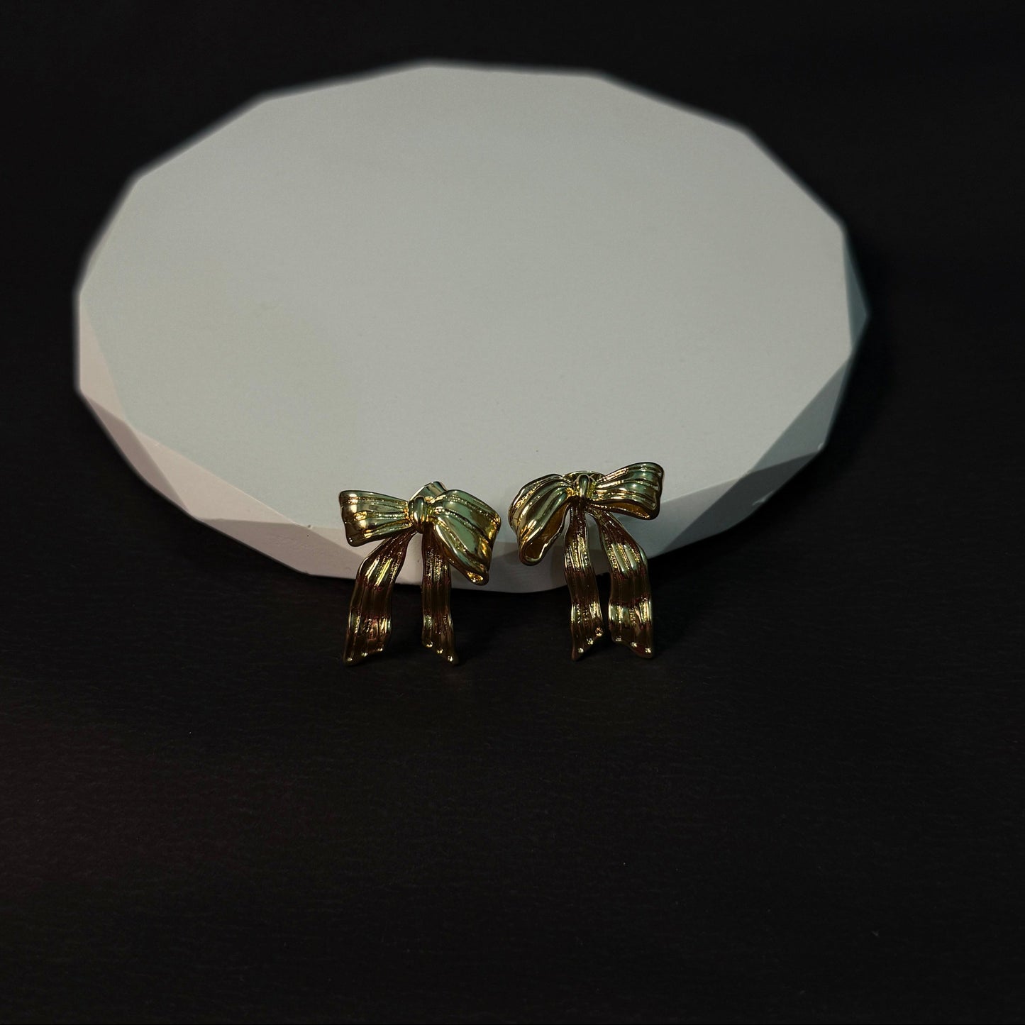 Two gold horse figurines on a white stone surface with a black background
