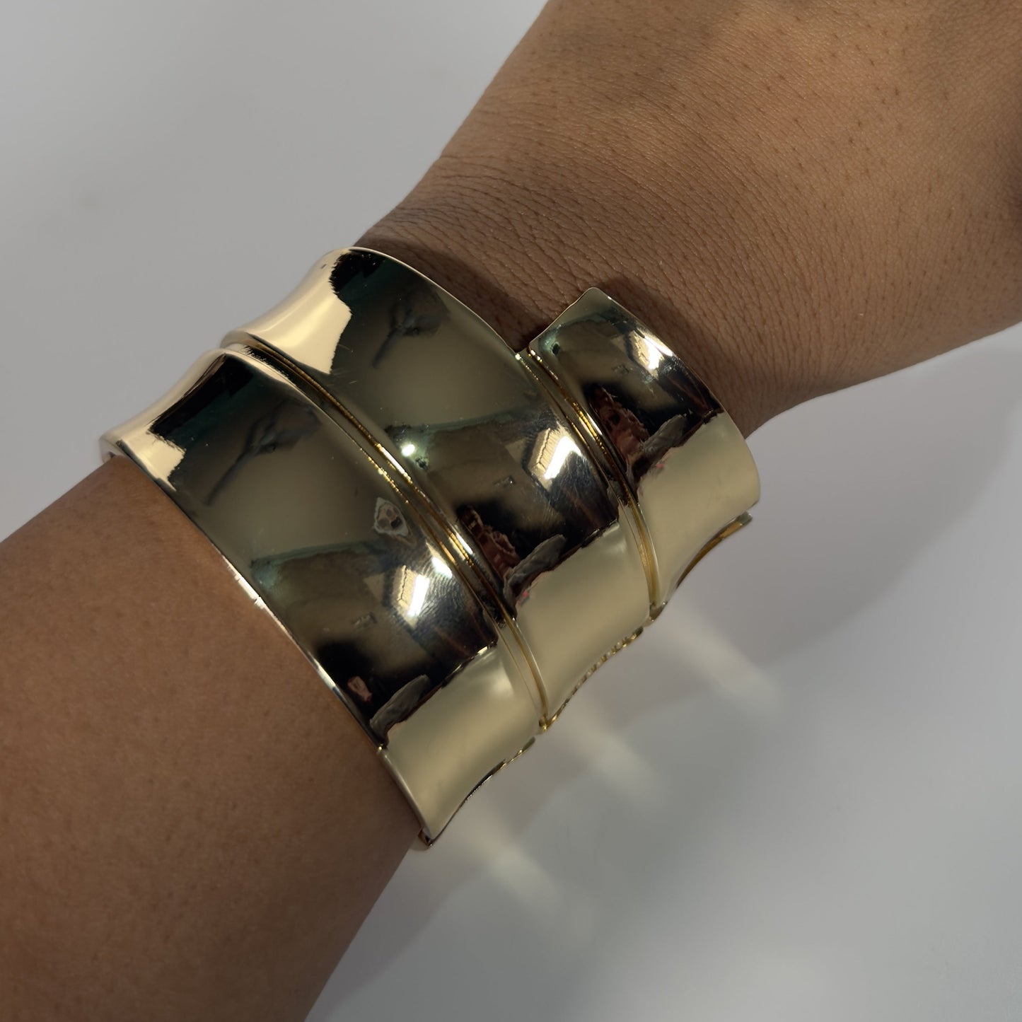 Gold bracelet on a wrist against a white background