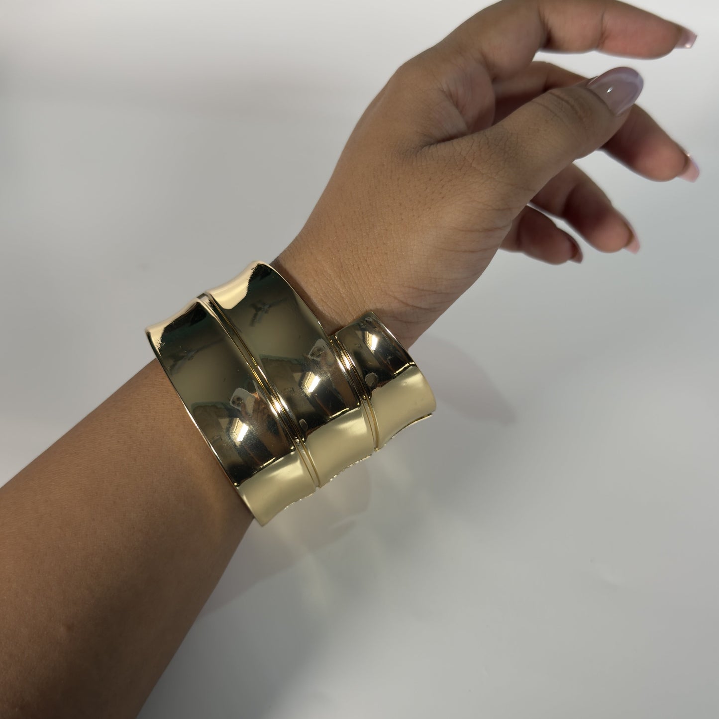 Gold bracelet on a wrist against a white background