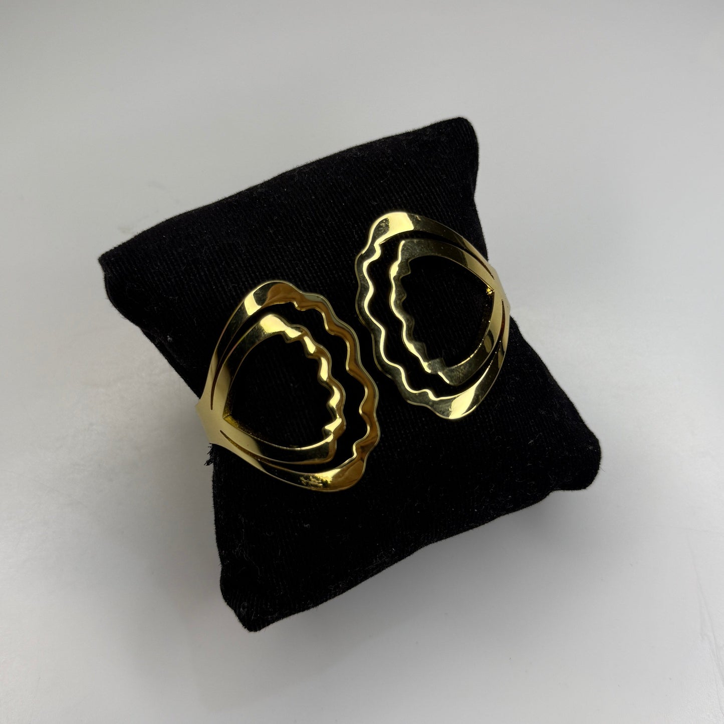 Gold hoop earrings on a black cushion against a light gray background