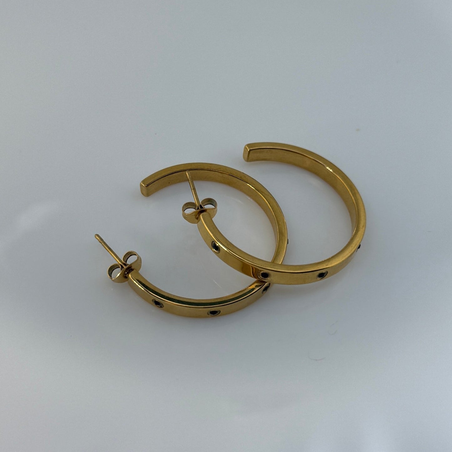 Gold hoop earrings on a white surface