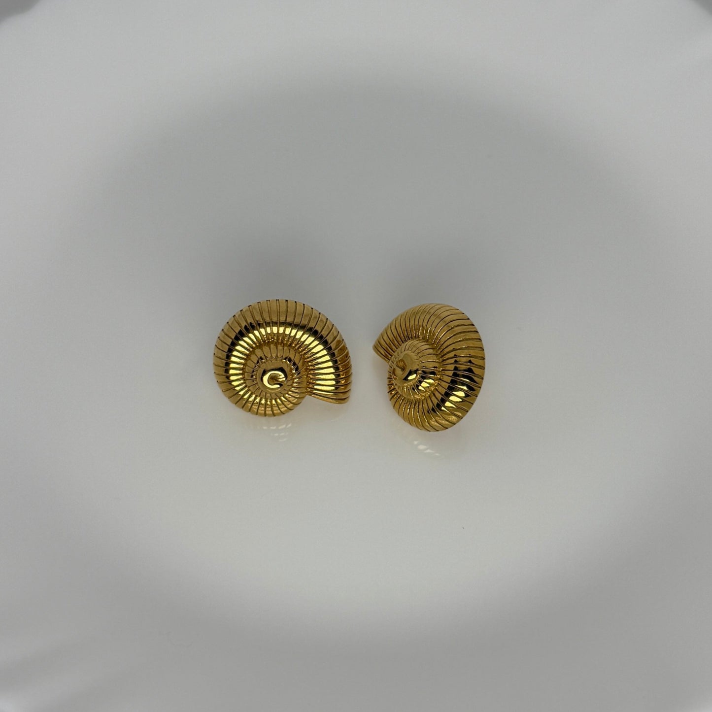 Gold spiral earrings on a white dish