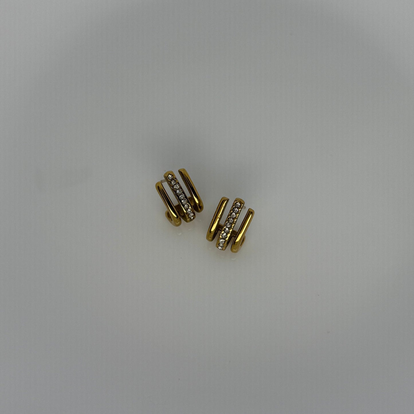 Gold earrings with small diamonds on a white plate