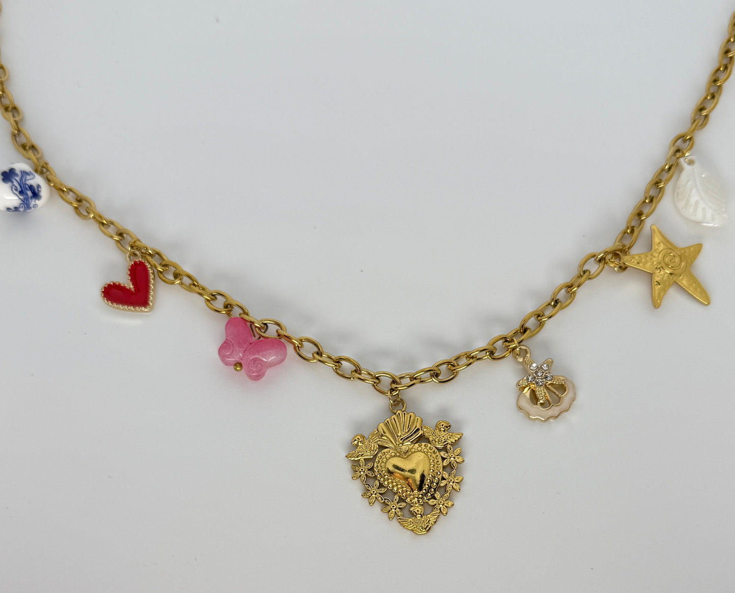 Gold necklace with various charms on a white background
