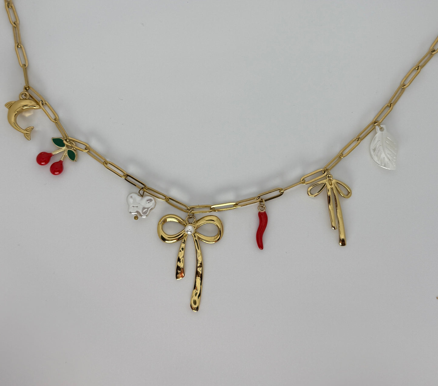Gold necklace with various charms on a light gray background