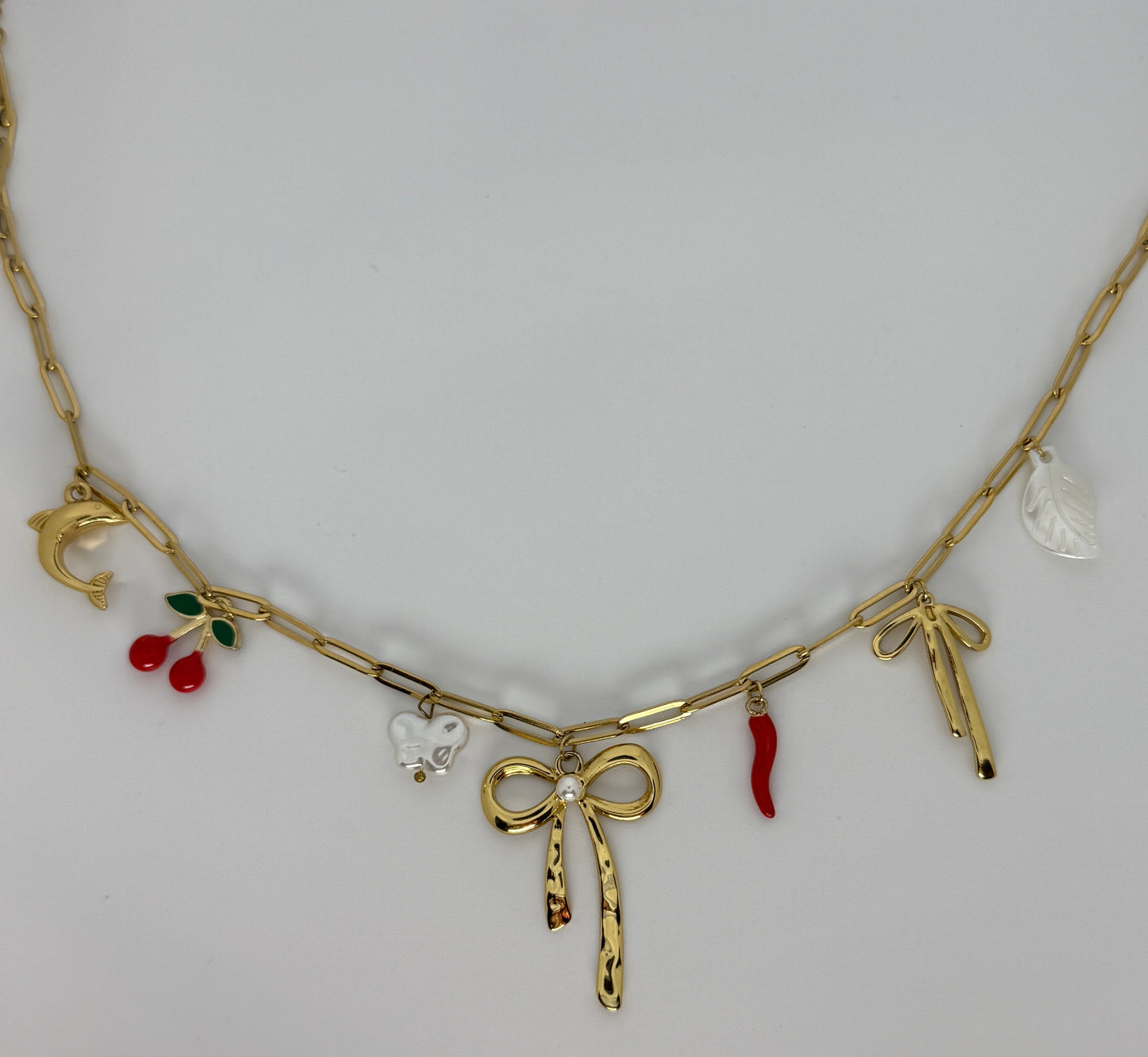 Gold necklace with various charms on a white background