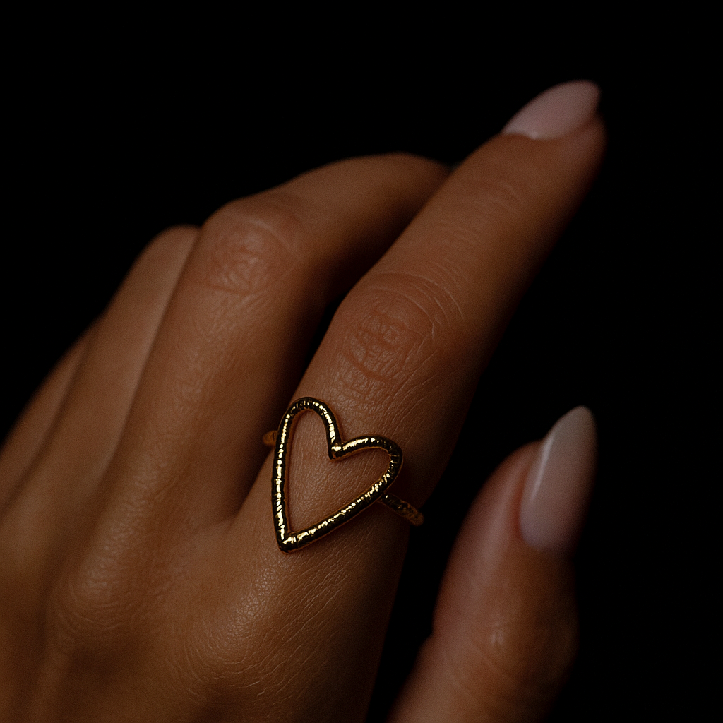 Heart-shaped ring on a hand with a dark background