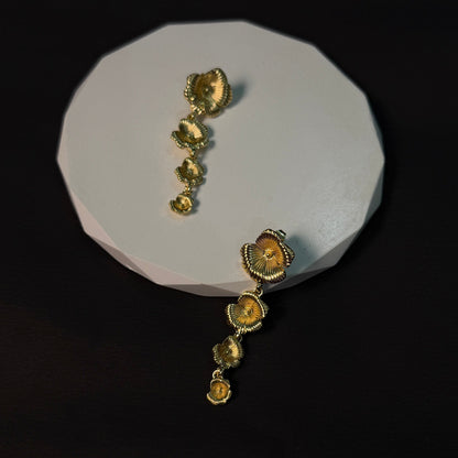 Gold earrings on a white stand against a black background