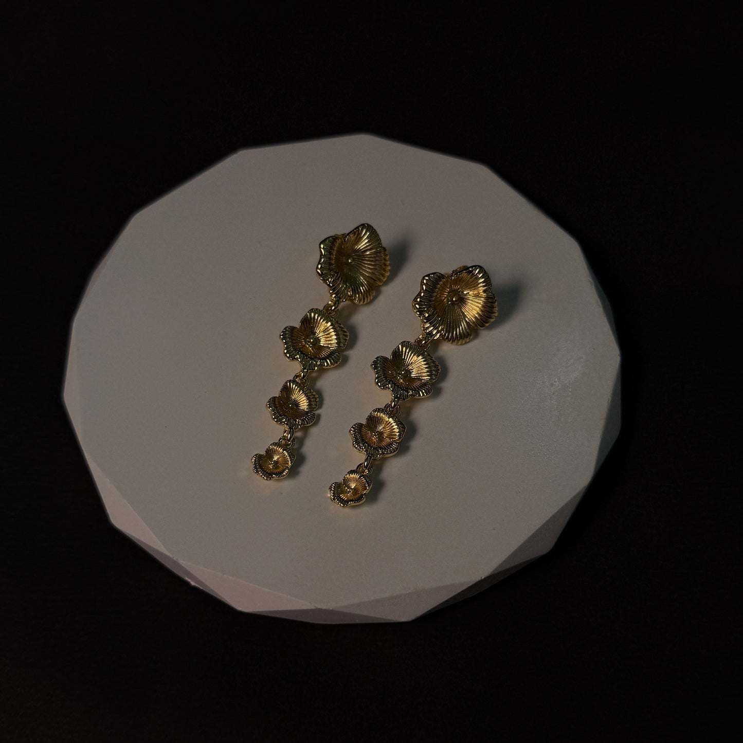 Gold jewelry pieces on a white stone surface with a black background