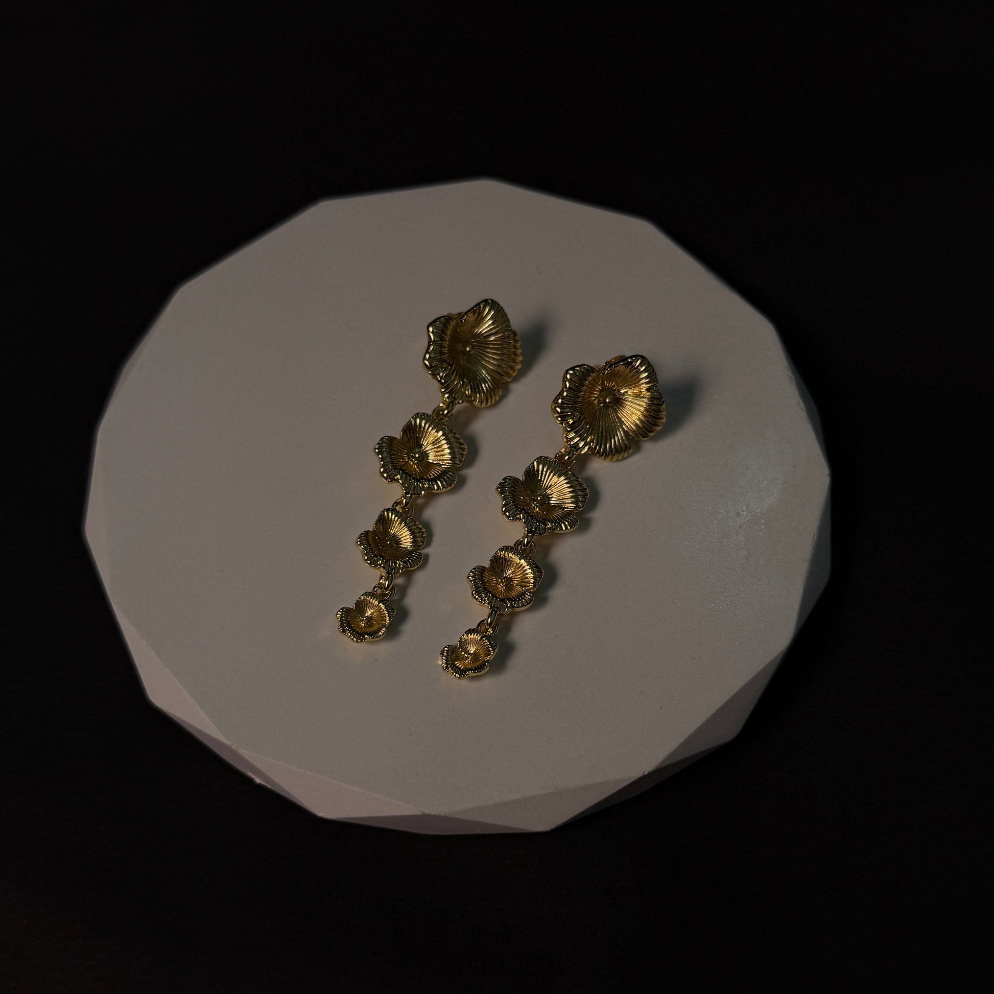 Gold jewelry pieces on a white stone surface with a black background