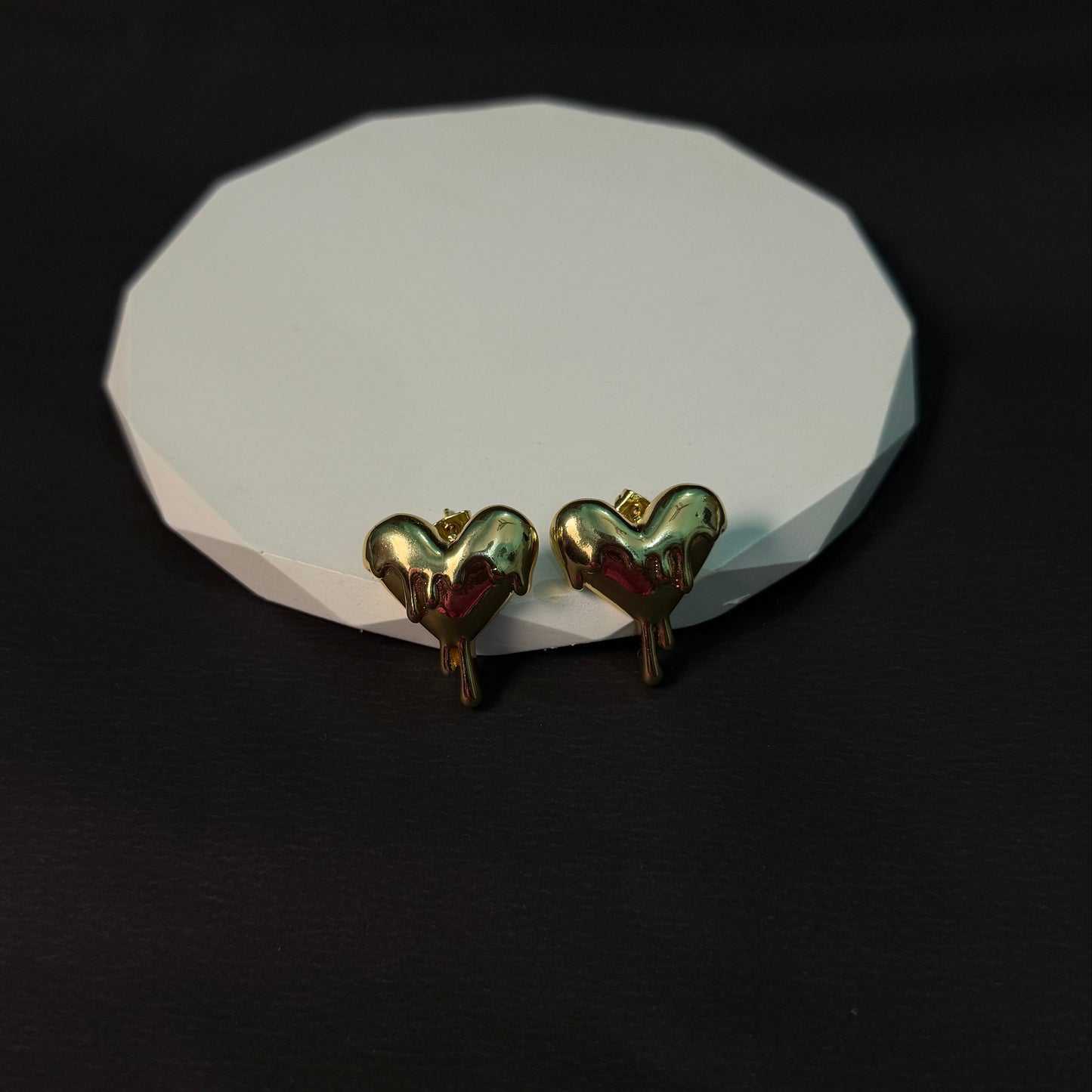 Heart-shaped earrings on a white stone surface with a black background
