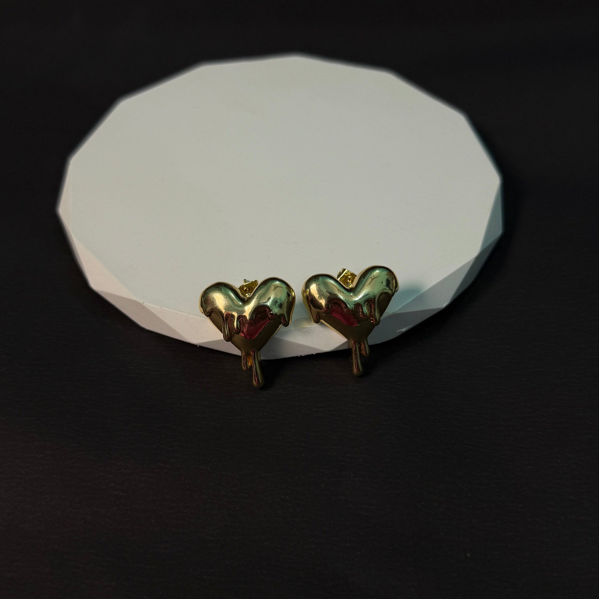Heart-shaped earrings on a white stone surface with a black background
