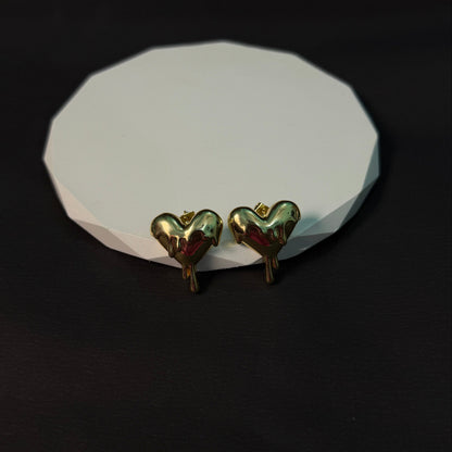 Heart-shaped earrings on a white stone surface with a black background