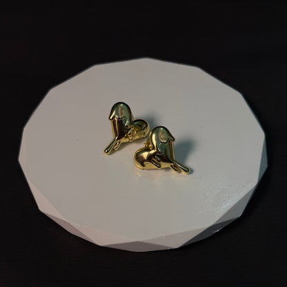 Gold bird-shaped earrings on a white stone surface with a black background