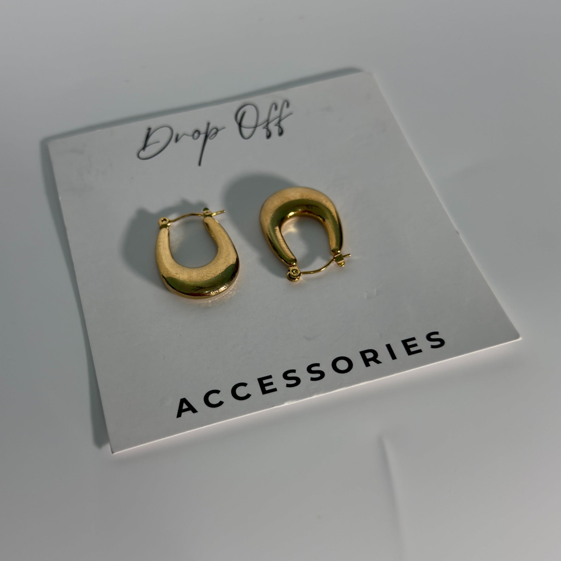 Gold hoop earrings on a 'Drop Off Accessories' card against a gray background