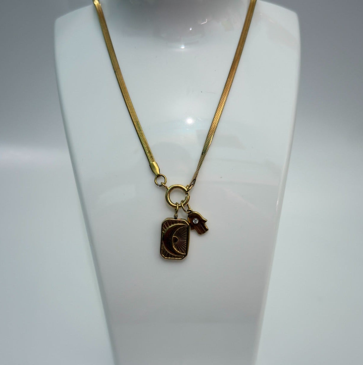 Gold necklace with a pendant on a white mannequin bust