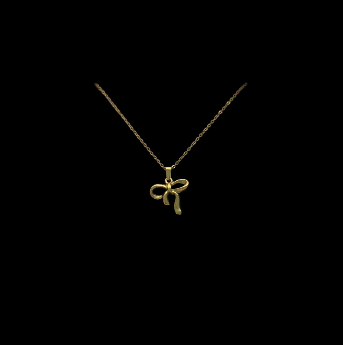 Gold necklace with a bow pendant in a white box on a gray background