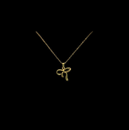 Gold necklace with a bow pendant in a white box on a gray background
