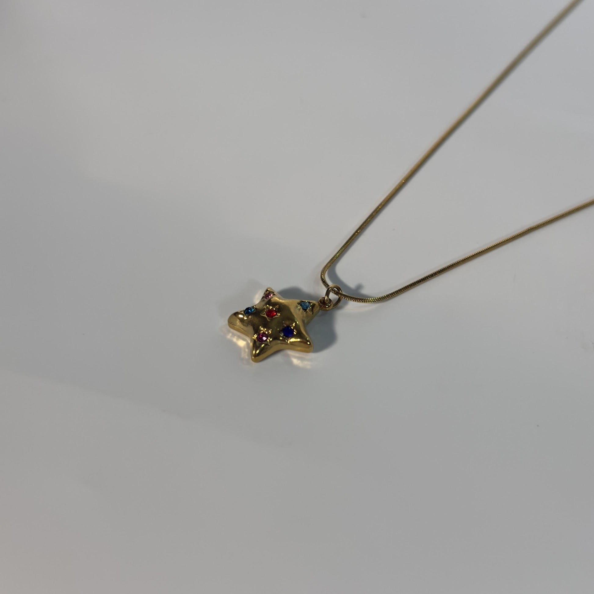 Gold necklace with a small pendant on a light gray background