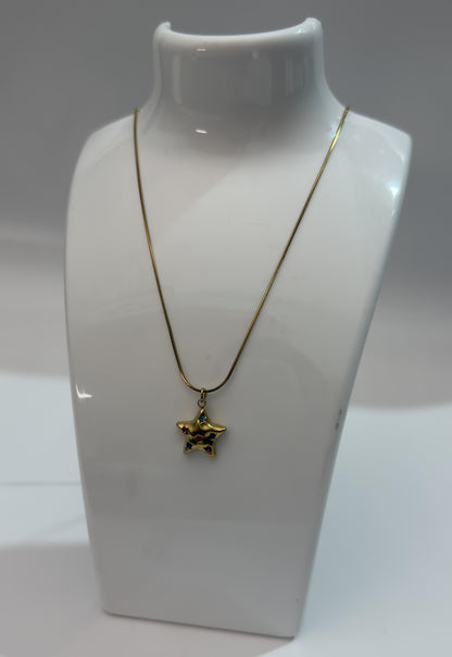 Gold necklace with a star-shaped pendant on a white mannequin bust.