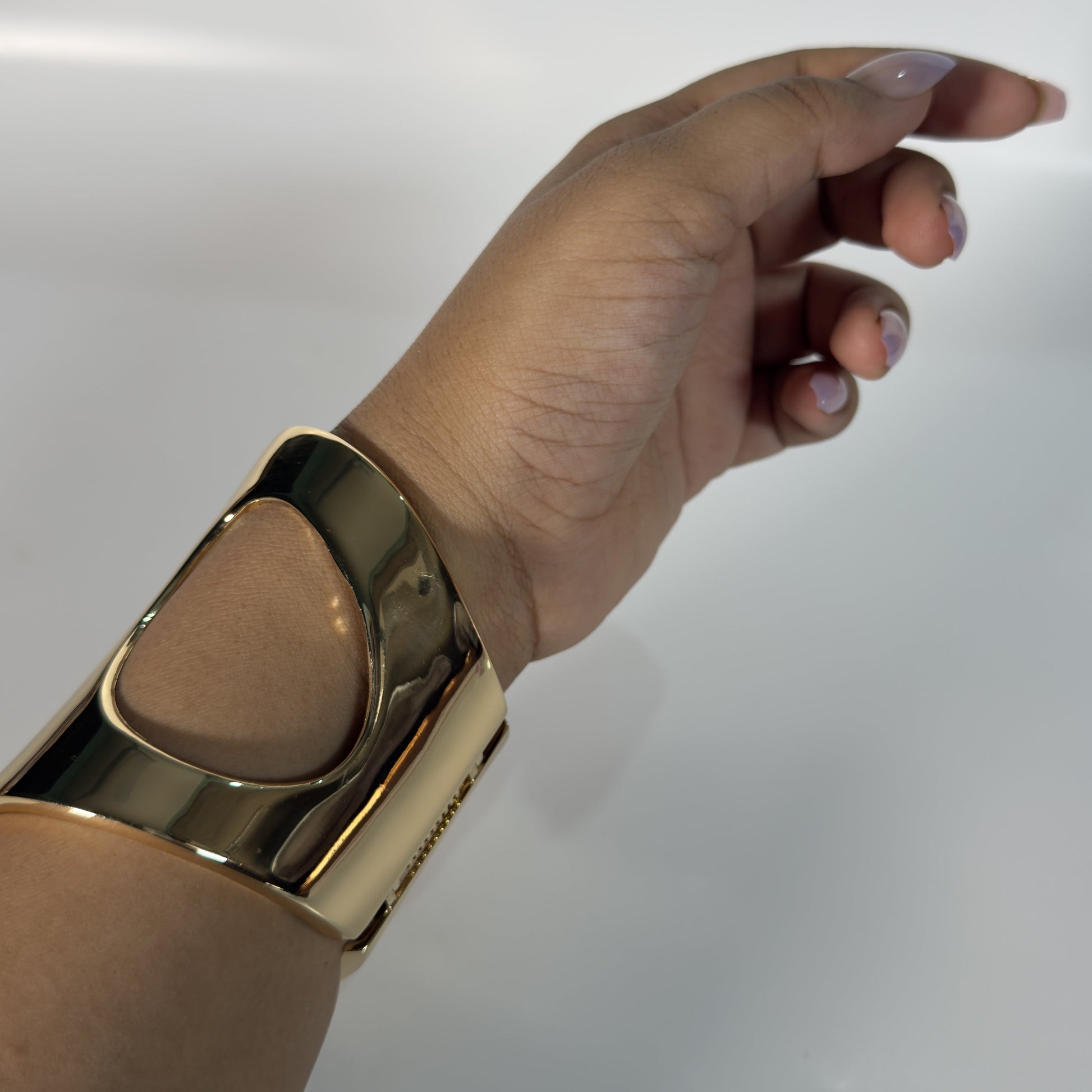 Hand wearing a gold bracelet on a white background