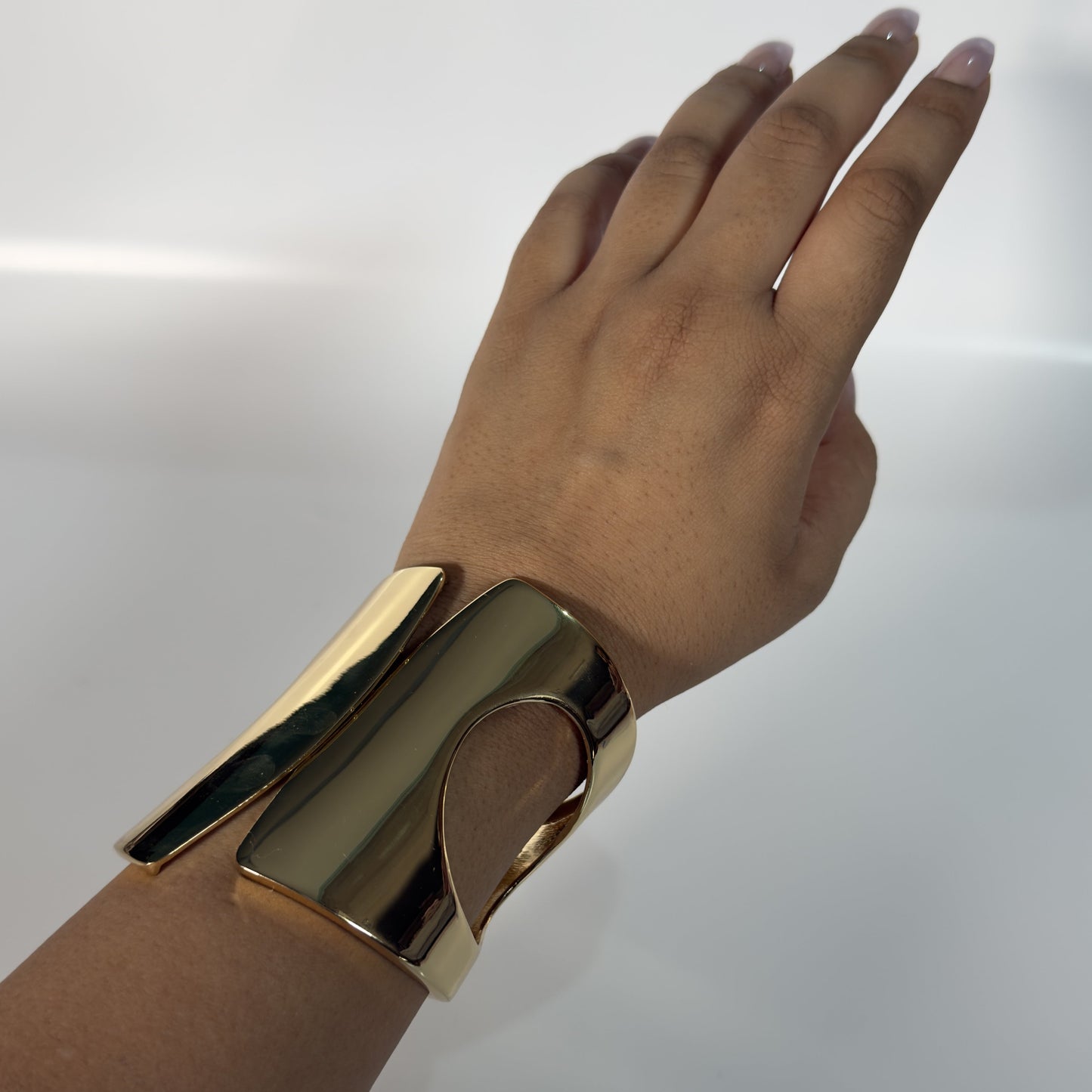 Gold bracelet on a wrist against a white background