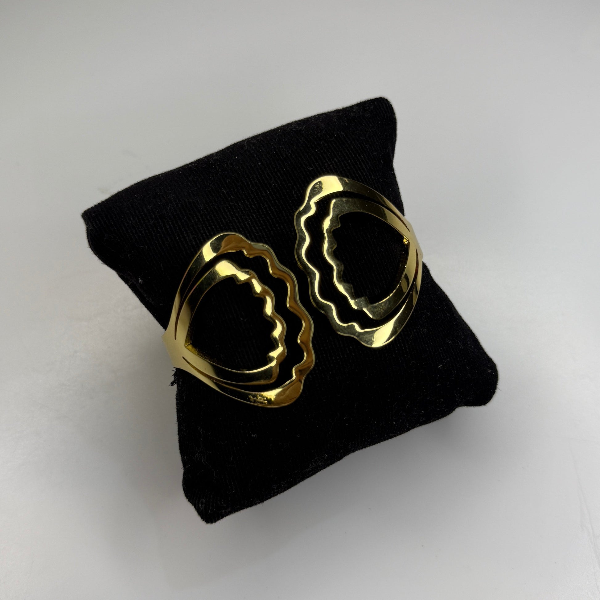 Gold hoop earrings on a black cushion against a light gray background