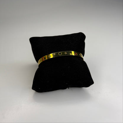 Gold bracelet on a black cushion against a white background