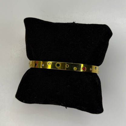 Gold bracelet on a black pillow against a white background