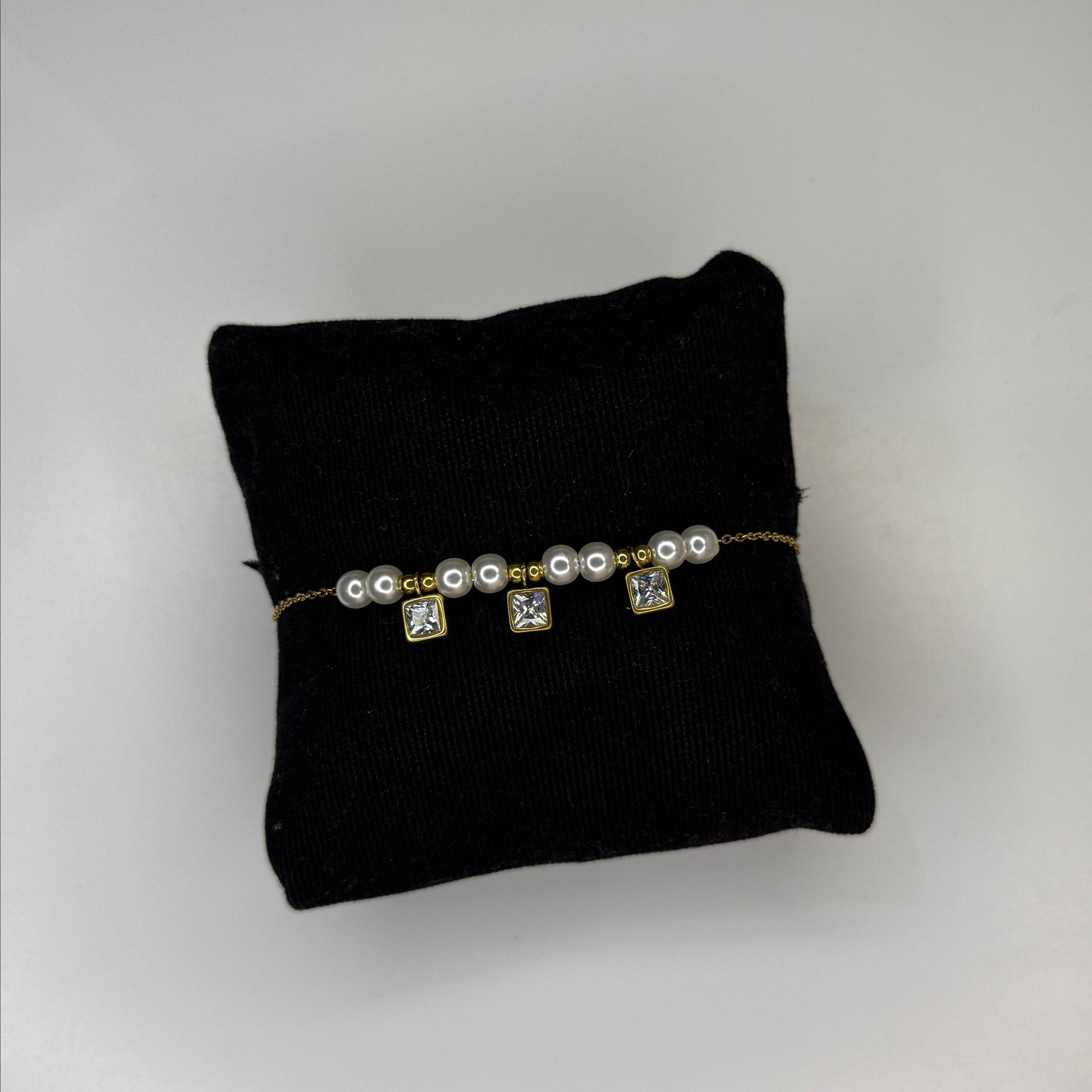 Pearl bracelet on a black cushion against a gray background