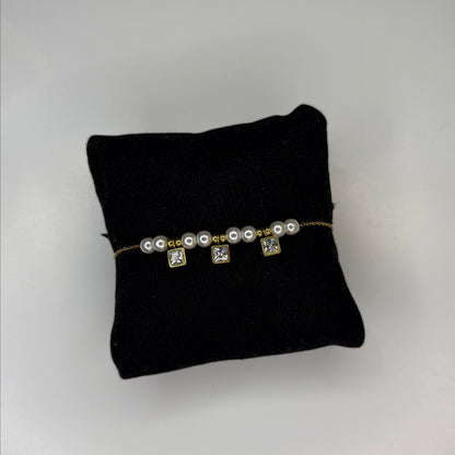 Pearl bracelet on a black cushion against a gray background