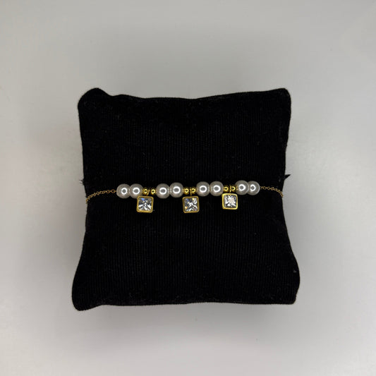 Pearl bracelet on a black cushion with a gray background