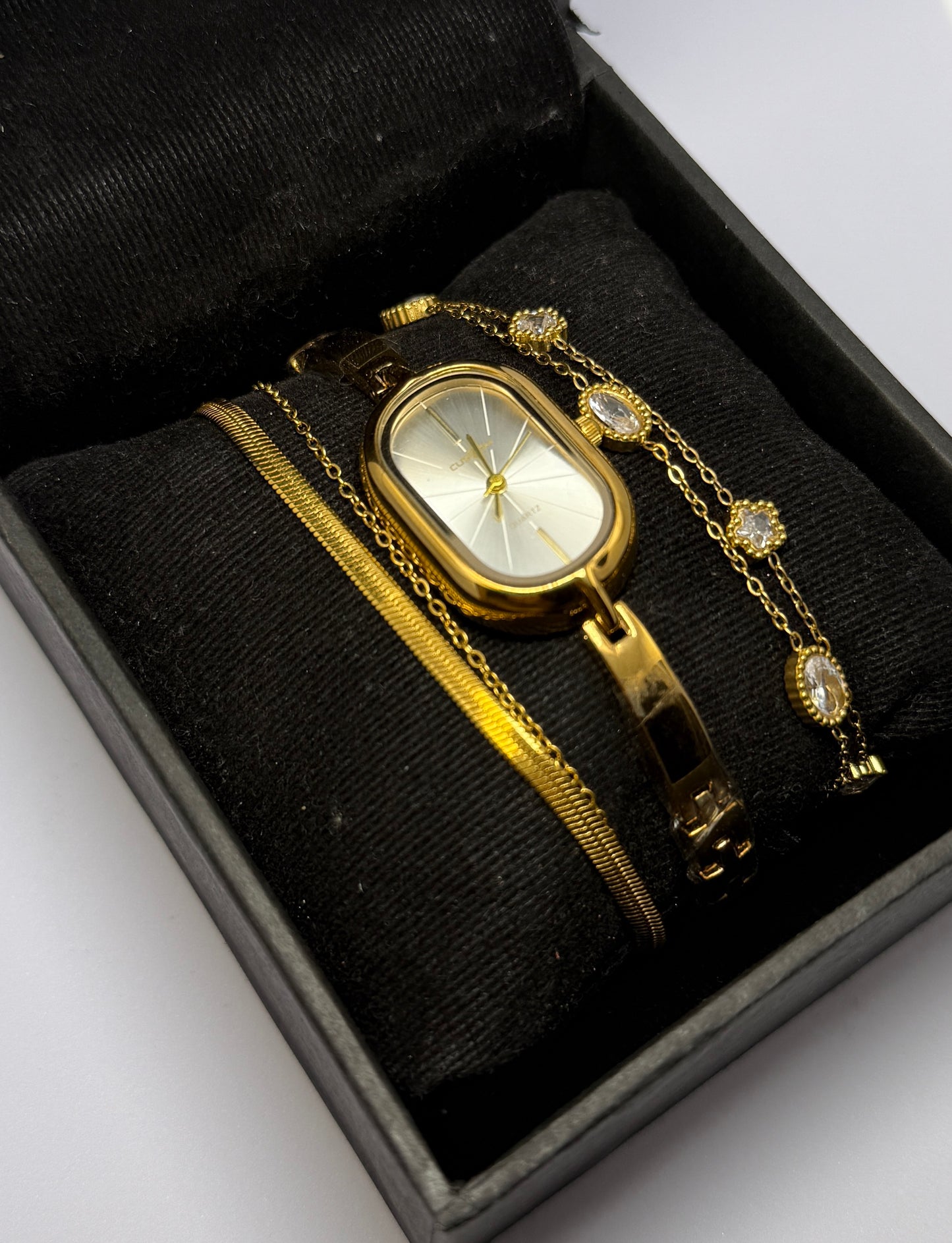 Gold watch with chain in a black box on a white background