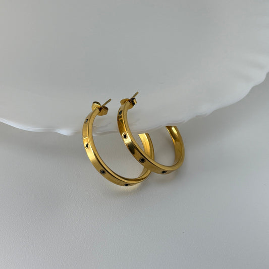 Gold hoop earrings on a white dish