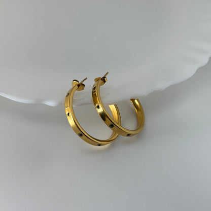 Gold hoop earrings on a white dish