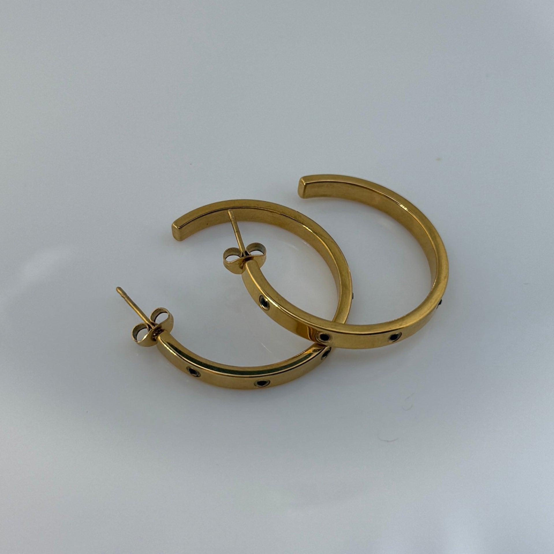Gold hoop earrings on a white surface