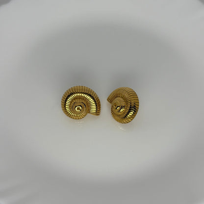 Gold spiral earrings on a white dish