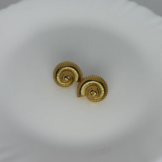 Pair of gold earrings on a white dish