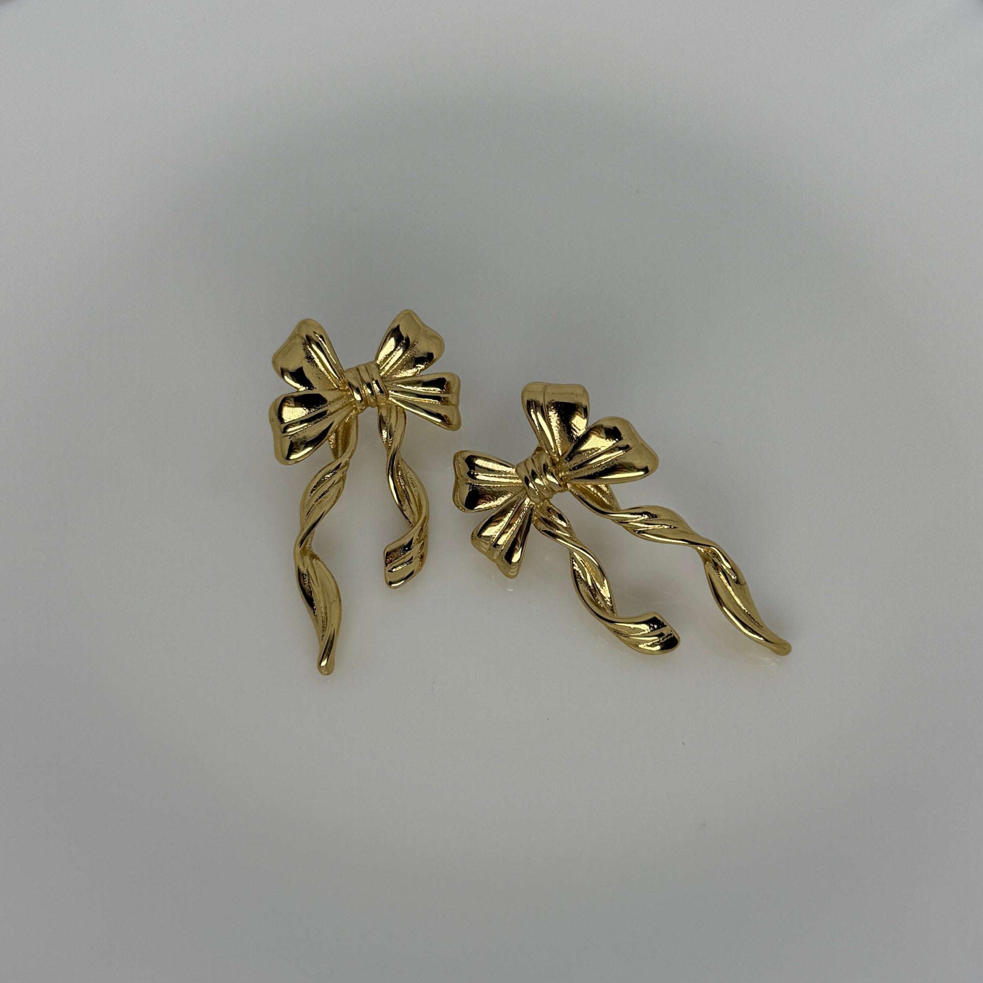 Gold bow-shaped earrings on a white background