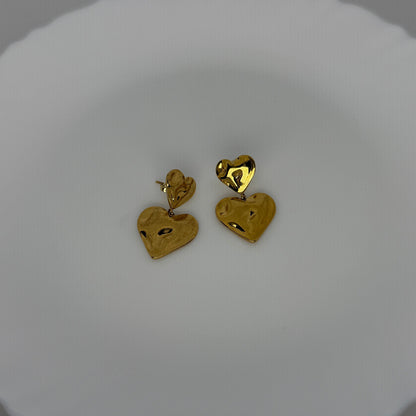 Gold heart-shaped earrings on a white dish