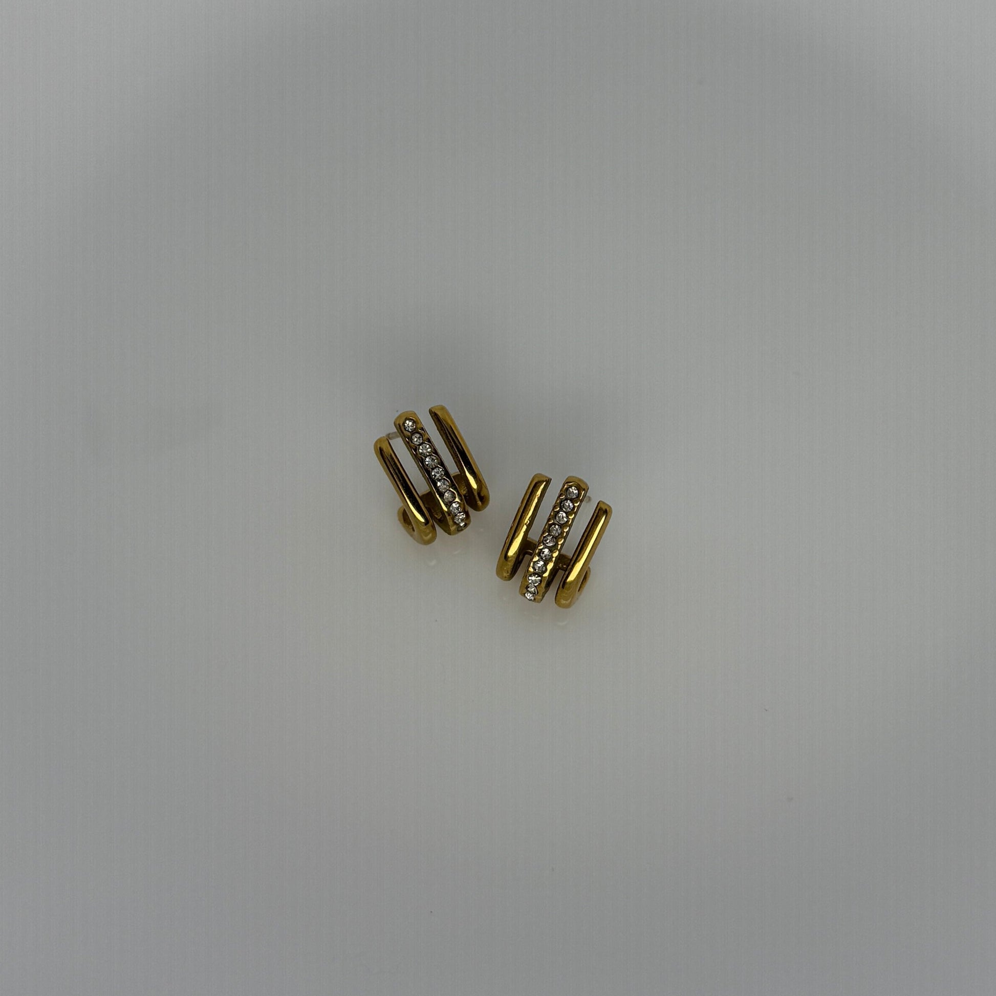 Gold earrings with small diamonds on a white plate