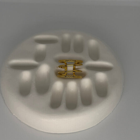 Gold ring on a white circular base with embossed design