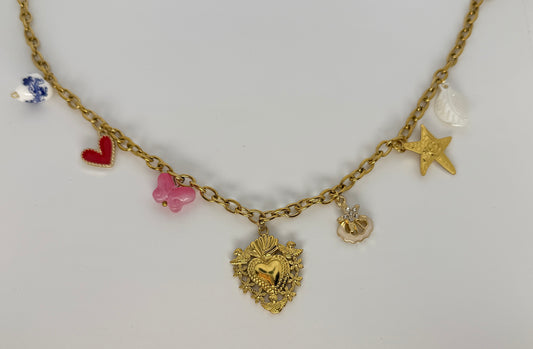 Gold necklace with various charms on a light gray background